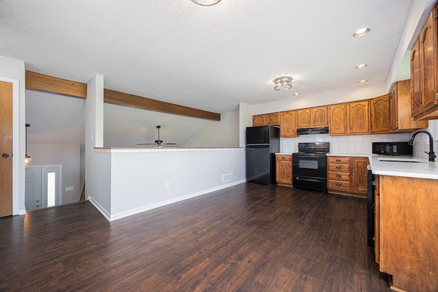 9721 State Rte 521, Sunbury, OH 43074 - kitchen featuring black appliances, a sink, under cabinet range hood, brown cabinets, and dark wood-style flooring