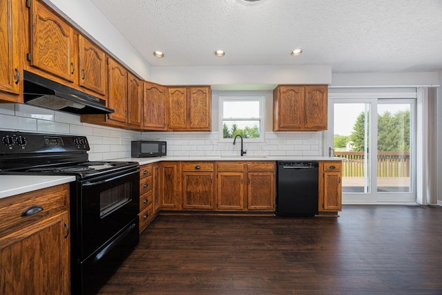 9721 State Rte 521, Sunbury, OH 43074 - kitchen featuring black appliances, under cabinet range hood, a sink, a textured ceiling, and dark wood-style flooring