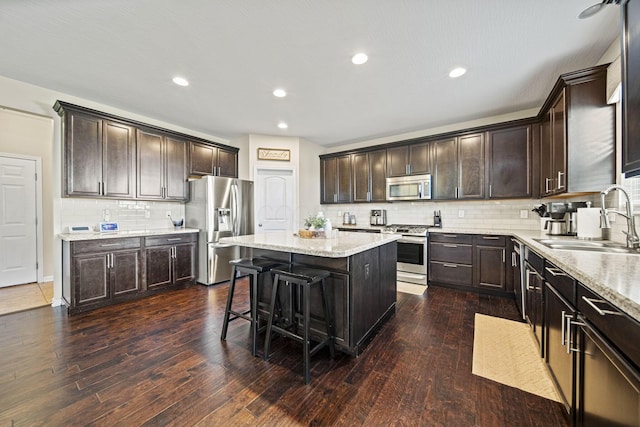 607 Green Forest Pl, Lithopolis, OH 43136 - kitchen with stainless steel appliances, a sink, dark brown cabinets, a center island, and decorative backsplash