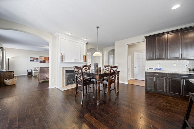 607 Green Forest Pl, Lithopolis, OH 43136 - dining area featuring arched walkways, dark wood-style flooring, baseboards, a tile fireplace, and recessed lighting