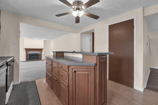1235 Belle Meade Pl, Westerville, OH 43081 - kitchen featuring light wood-type flooring, brown cabinetry, open floor plan, a fireplace, and a ceiling fan
