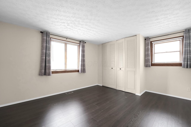 1235 Belle Meade Pl, Westerville, OH 43081 - unfurnished bedroom with multiple windows, a textured ceiling, dark wood finished floors, baseboards, and a closet