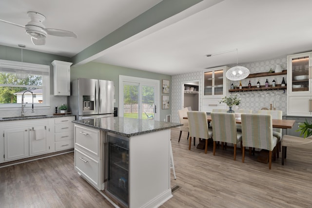 6235 George Fox Dr, Galloway, OH 43119 - kitchen with wine cooler, stainless steel fridge with ice dispenser, open shelves, dark stone counters, and white cabinets