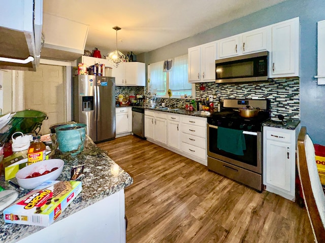 329 S Terrace Ave, Columbus, OH 43204 - kitchen featuring stainless steel appliances, white cabinetry, wood finished floors, backsplash, and hanging light fixtures