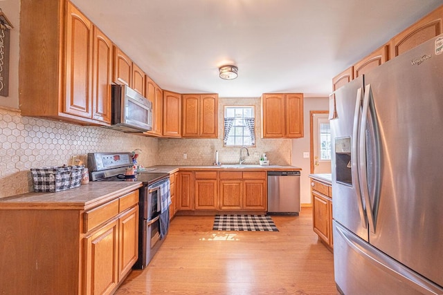 1485 E Choctaw Dr, London, OH 43140 - kitchen with stainless steel appliances, a sink, light wood-style flooring, tasteful backsplash, and light countertops