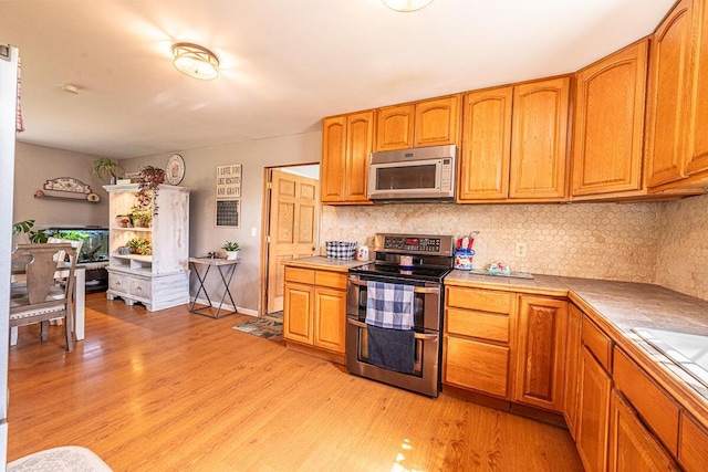 1485 E Choctaw Dr, London, OH 43140 - kitchen featuring range with two ovens, tile countertops, light wood-type flooring, and decorative backsplash
