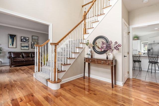 stairway featuring hardwood / wood-style floors, baseboards, and ornamental molding