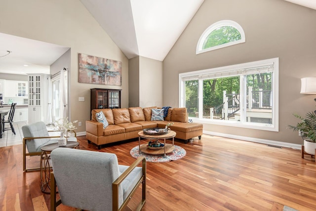 living room with high vaulted ceiling, wood finished floors, and baseboards