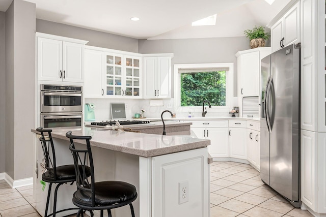kitchen featuring stainless steel appliances, a center island with sink, light tile patterned flooring, white cabinetry, and recessed lighting
