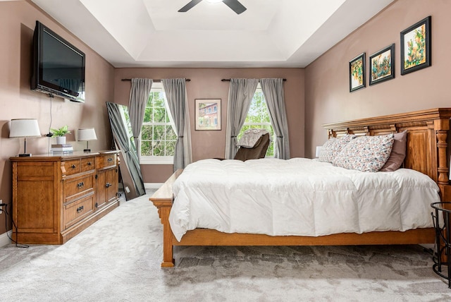 carpeted bedroom featuring a raised ceiling and ceiling fan