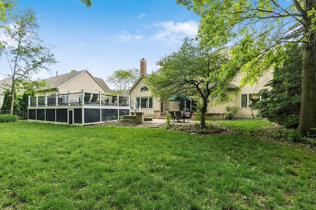 back of house featuring stucco siding, a lawn, a patio area, a wooden deck, and a chimney