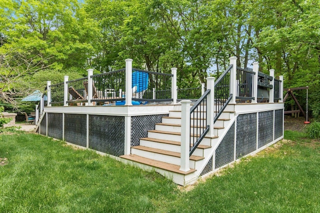 view of swimming pool featuring stairway, a wooden deck, a lawn, and view of wooded area