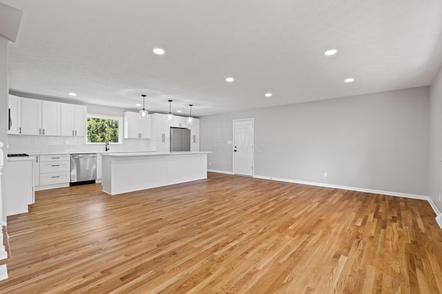 unfurnished living room with recessed lighting, light wood finished floors, baseboards, and a sink