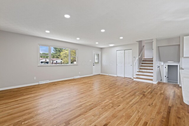 unfurnished living room featuring stairs, recessed lighting, light wood-type flooring, and baseboards