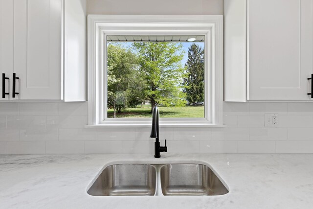 kitchen featuring a sink, white cabinets, decorative backsplash, and light stone counters