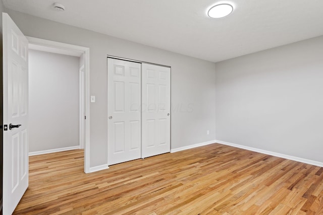 unfurnished bedroom with light wood-style floors, baseboards, and a closet