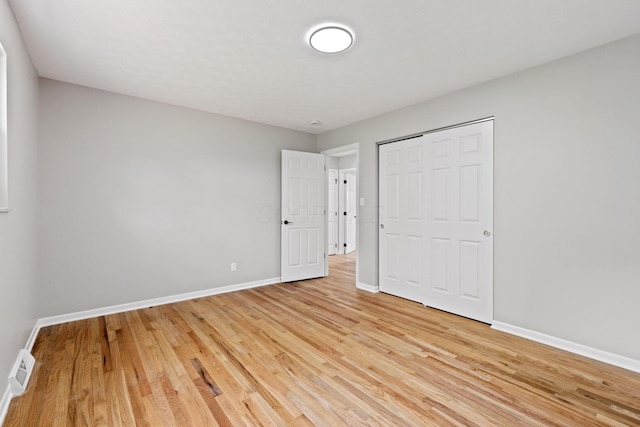 unfurnished bedroom with light wood finished floors, baseboards, and a closet