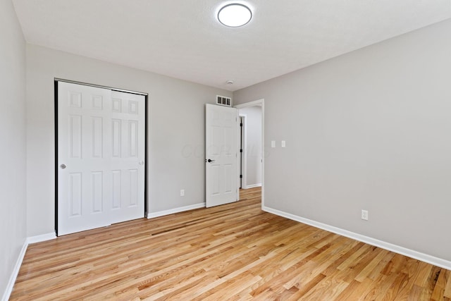 unfurnished bedroom with light wood-type flooring, baseboards, and a closet