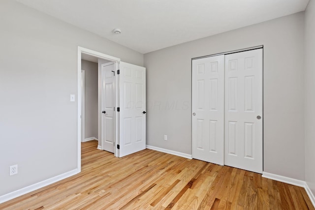 unfurnished bedroom with light wood finished floors, baseboards, and a closet