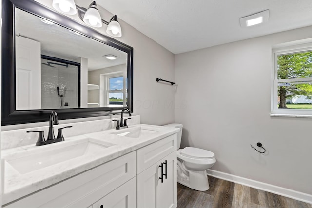 full bathroom with wood finished floors, toilet, a shower with door, double vanity, and baseboards