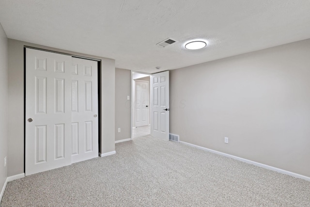 unfurnished bedroom featuring carpet, baseboards, a closet, and a textured ceiling