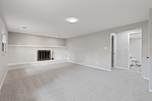 unfurnished living room with carpet, baseboards, and a brick fireplace