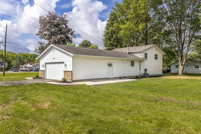 view of front facade featuring a front lawn, asphalt driveway, a garage, and central AC unit