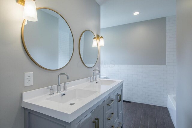 778 S 17th St, Columbus, OH 43206 - full bathroom with tile walls, double vanity, a tub, wood finished floors, and a wainscoted wall