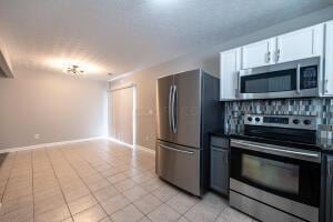 kitchen featuring appliances with stainless steel finishes, white cabinetry, tasteful backsplash, and dark countertops