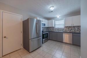 kitchen with stainless steel appliances, decorative backsplash, dark countertops, and light tile patterned floors