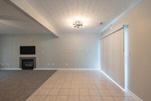 unfurnished living room featuring a fireplace, tile patterned flooring, and baseboards