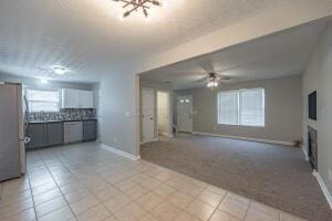 unfurnished living room with baseboards, light tile patterned floors, ceiling fan, and a fireplace
