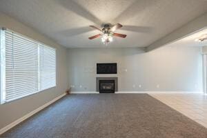 unfurnished living room featuring baseboards, carpet, ceiling fan, and a fireplace
