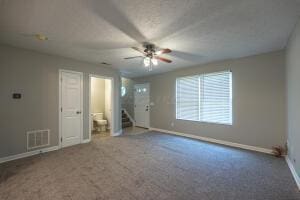unfurnished living room with carpet flooring, baseboards, a ceiling fan, and stairway