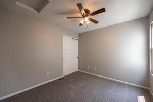 empty room with attic access, baseboards, ceiling fan, and carpet flooring