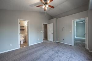 unfurnished bedroom with baseboards, vaulted ceiling, carpet floors, a walk in closet, and ensuite bathroom