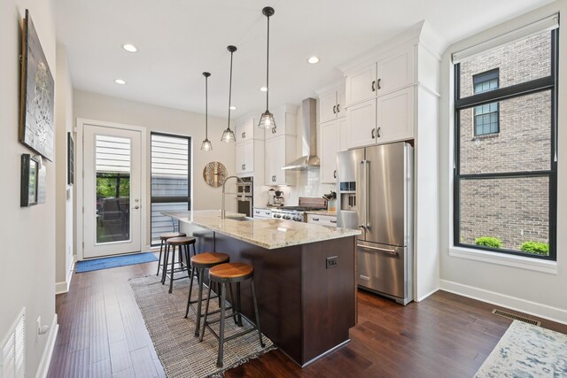 304 Cornelius St, Columbus, OH 43215 - kitchen with high end refrigerator, wall chimney exhaust hood, baseboards, a kitchen island with sink, and white cabinets
