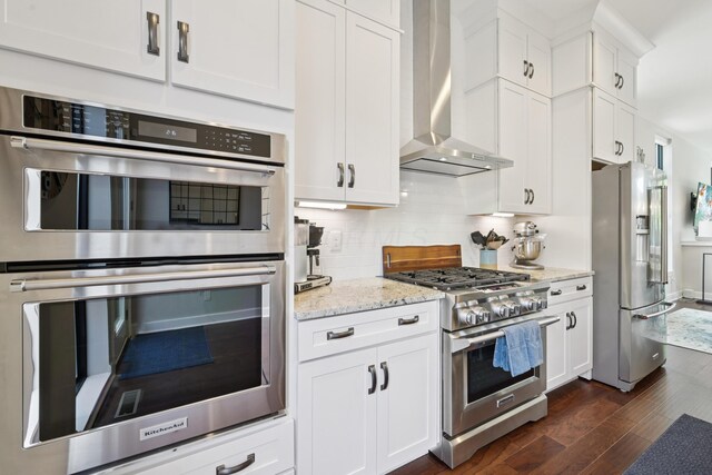 304 Cornelius St, Columbus, OH 43215 - kitchen with appliances with stainless steel finishes, wall chimney exhaust hood, decorative backsplash, dark wood finished floors, and white cabinetry