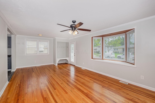 unfurnished living room with a ceiling fan, healthy amount of natural light, baseboards, and crown molding