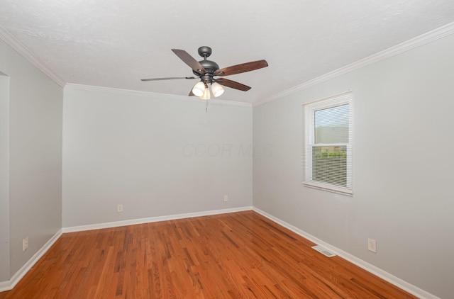 empty room with wood finished floors, ceiling fan, baseboards, and crown molding