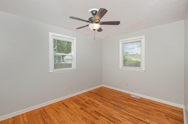 spare room featuring baseboards, light wood finished floors, and a ceiling fan