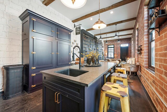 43-45 W Markison Ave, Columbus, OH 43207 - kitchen with a sink, dark wood finished floors, beam ceiling, brick wall, and an island with sink