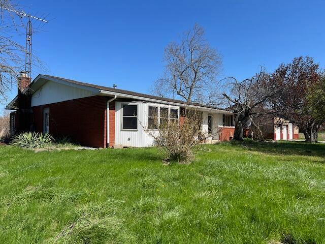 1886 Johnstown Utica Rd NE, Utica, OH 43080 - view of property exterior featuring a chimney, brick siding, and a lawn