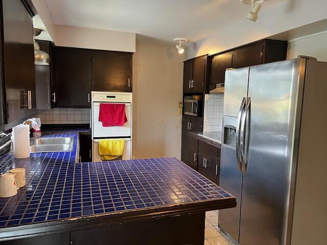 1886 Johnstown Utica Rd NE, Utica, OH 43080 - kitchen with stainless steel appliances, a sink, tile counters, and tasteful backsplash