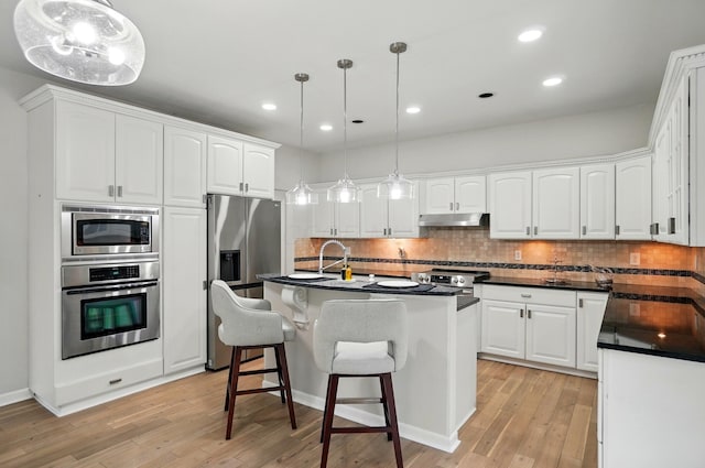 1940 Scioto Pointe Dr, Columbus, OH 43221 - kitchen with appliances with stainless steel finishes, under cabinet range hood, dark countertops, light wood-style floors, and recessed lighting