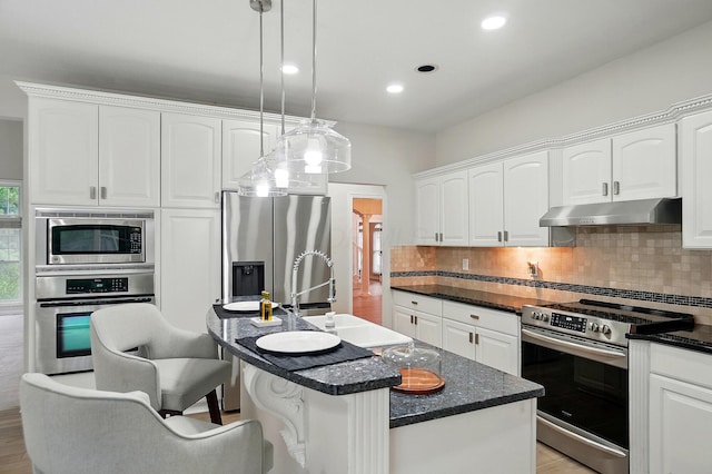 1940 Scioto Pointe Dr, Columbus, OH 43221 - kitchen with under cabinet range hood, stainless steel appliances, tasteful backsplash, white cabinets, and a breakfast bar area