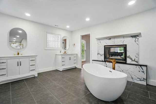 1940 Scioto Pointe Dr, Columbus, OH 43221 - full bathroom featuring two vanities, a freestanding bath, recessed lighting, healthy amount of natural light, and tile patterned flooring