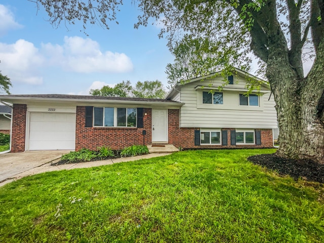 split level home featuring a garage, a front yard, driveway, and brick siding
