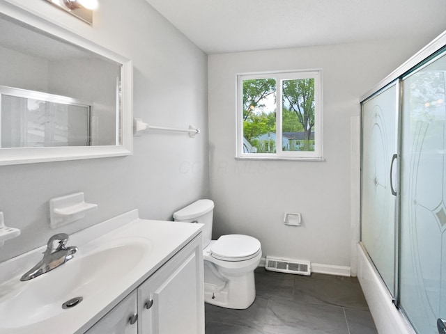bathroom featuring toilet, vanity, enclosed tub / shower combo, and baseboards