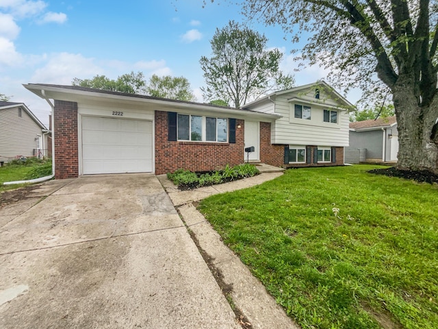 tri-level home with an attached garage, a front yard, brick siding, and concrete driveway